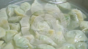 Closeup of spooning around Chinese chives dumplings in pot, cooking handmade dumplings in boiling water