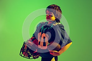 Closeup sportive strong kid, american football player in blue sports uniform and protective equipment posing isolated on