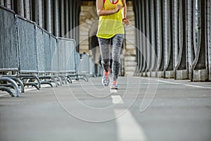 Closeup on sportswoman running on Pont de Bir-Hakeim bridge