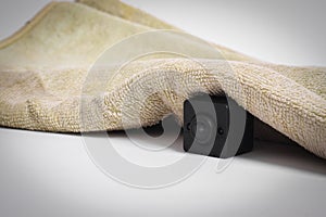 Closeup spy camera under cloth on white background