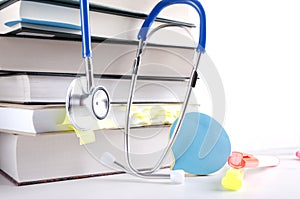 Closeup of stack of books, stethoscope and stationary on the white table