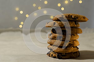 Closeup of stack of chocolate cookies on the baking papar against garland bokeh.Empty space photo