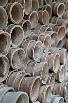 Closeup of stacks of old used weathered terra cotta flower pots in gardening shed