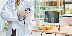 Closeup of standing asian nutritionist doctor woman holding stethoscope