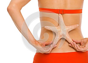 Closeup on starfish in hand of woman in swimsuit