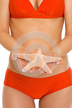 Closeup on starfish in hand of woman in swimsuit