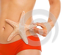 Closeup on starfish in hand of woman in swimsuit
