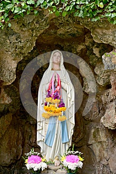 Statue of Our lady of grace virgin Mary view with natural background in the rock cave at Thailand. selective focus.