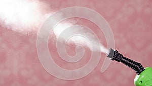 Closeup steam exiting nozzle of vapor cleaning machine, pink background