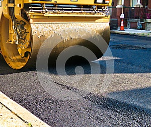Steamroller compacts asphalt in road repaving project. photo