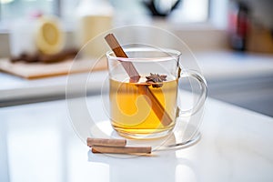 closeup of a steamy hot toddy in a clear mug with a cinnamon stick