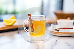 closeup of a steamy hot toddy in a clear mug with a cinnamon stick