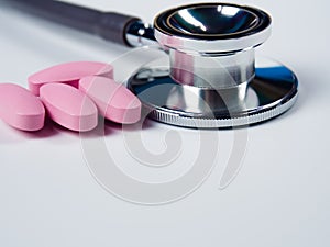 Closeup, stethoscope and pink pills .