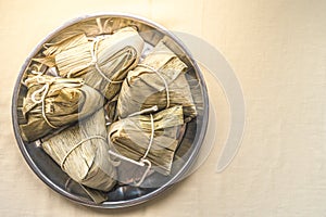 Closeup Sticky rice dumpling or Zongzi on stainless steel tray for Dragon Boat Festival on cream color fabric. Pay respect to ance