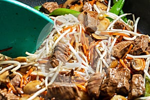 Closeup of Stir-fry in a skillet being mixed with a spatula.