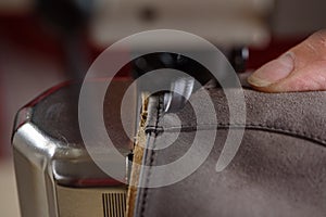 Closeup of stitching leather shoes on industrial sewing machine. Manufacturing of craft handmade leather shoes