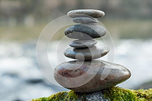 Stone balance on rock covered by moss in border river