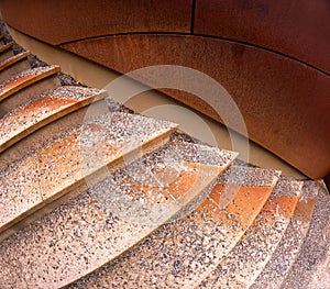 Closeup of stone steps and wall in orange material with gravel on the steps