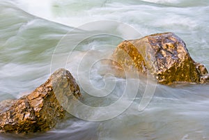 Stones among emerald rushing mountain river