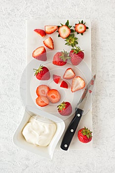 Closeup of Strawberries, Whipped Cream and Knife on Marble Cutting Board