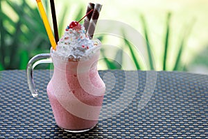 Closeup strawberry smoothies milkshake with whip cream and cherry for topping. Cold drink concept