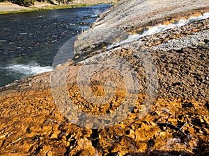 Closeup of stream of steaming water flowing into river at Yellowstone National Park