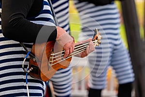 Closeup of a street musician playing the ukulele in a park