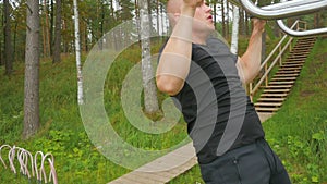 Closeup of strong athlete doing pull-up on horizontal bar.