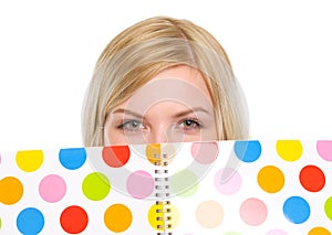 Closeup on student girl hiding behind notebook