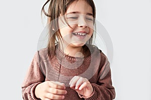 Closeup studio horizontal portrait of happy cute little girl smiling joyful and wearing sweater isolated on a white studio