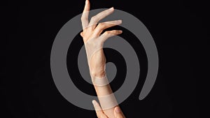 Closeup studio shot of beautiful caucasian woman showing and touching her hand soft natural skin isolated on black