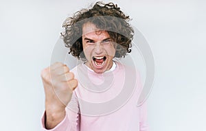 Closeup studio shot of mad furious man scream at someone, clenches fists as can`t control emotions, shouts loudly and with anger,