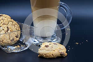 Closeup studio shot of three layered tea drink  and chocolate chip cookies with dark blue background