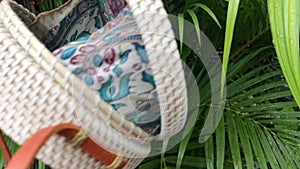 Closeup of stylish handmade rattan handbag on a tropical background. Bali island.