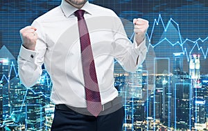 Closeup of successful portfolio manager in white shirt with pumped fists. A concept of the celebrating of success. Forex chart and