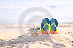 Closeup of Summer beach with blue flip flops and sunglasses on starfish in tropical beach