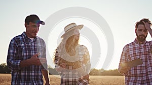 Closeup at sunset farmer have a discussion with other young guy and woman they walking through the wheat field and