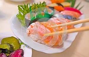 Closeup sushi with chopsticks In white plate . Japanese style Food