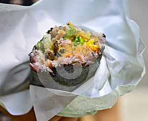 Closeup of sushi hand roll with colorful meat and veggie fillings