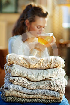 Closeup on sweaters and woman enjoying tea in background