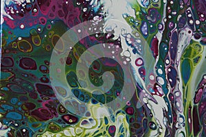 Closeup of a swirling abstract acrylic pour painting with blending greens, blues, and purples.