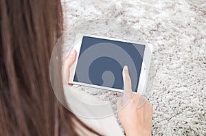 Closeup tablet computer on woman hand and point by finger on blurred gray carpet floor textured background with copy space