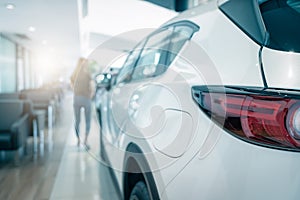 Closeup tail light of white SUV car parked in luxury showroom. Car dealership office. Rear view new car in modern showroom. Car