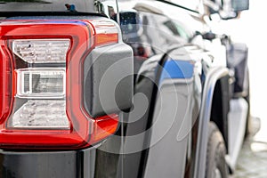 Closeup of a taillight on a modern black car with reflection. Shallow depth of field. Selective focus