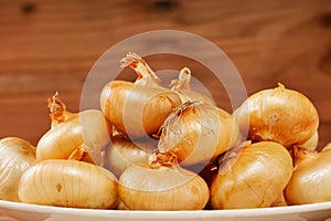 Closeup of tasty Uncooked Italian borettane onions with blur wooden background