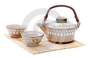 Closeup of teapot and teacup set Japanese style put on bamboo mat isolated on white background