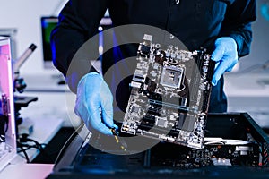Closeup of technician installing motherboard inside computer case in modern lab, symbolizing innovation, hardware repair