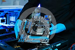 Closeup of technician installing motherboard inside computer case in modern lab, symbolizing innovation, hardware repair