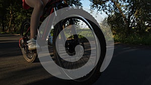 Closeup teen legs and bike wheels riding on road