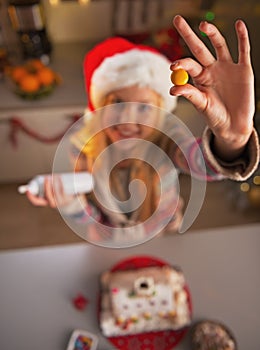 Closeup on teenage girl in santa hat showing candie in kitchen photo